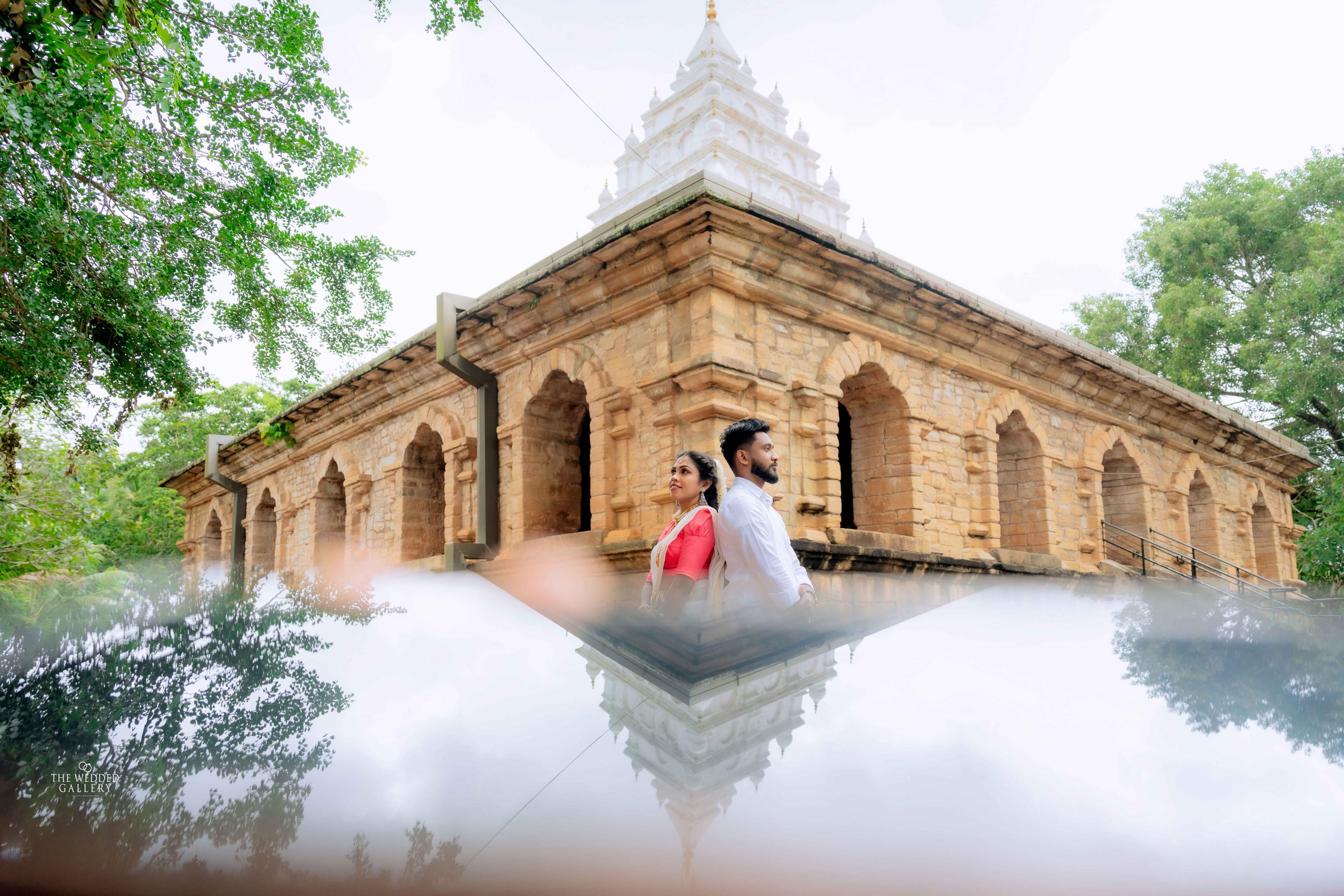 Couple reflected in still water in front of an ancient brick temple